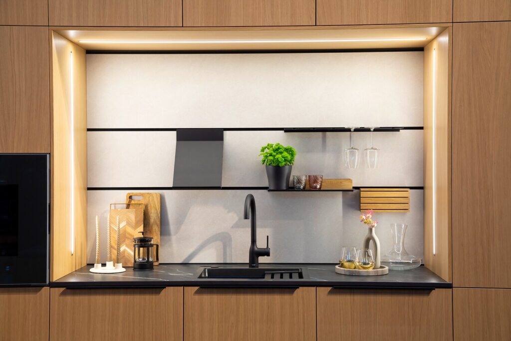 Moderne Ballerina Küchenzeile mit eleganter Holzoptik, schwarzer Armatur, offenen Regalen und integrierter Beleuchtung für ein stilvolles, warmes Ambiente.